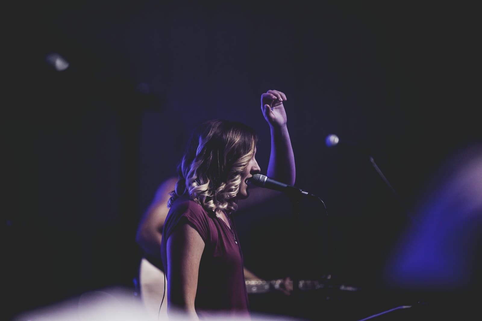 Singer-songwriter performing with a microphone in a warm studio