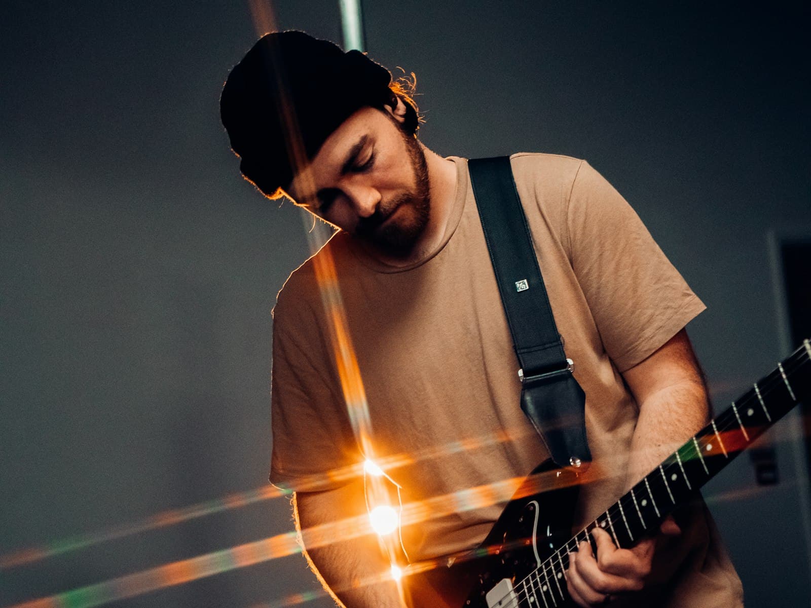 Musician absorbed in playing electric guitar in warm studio light