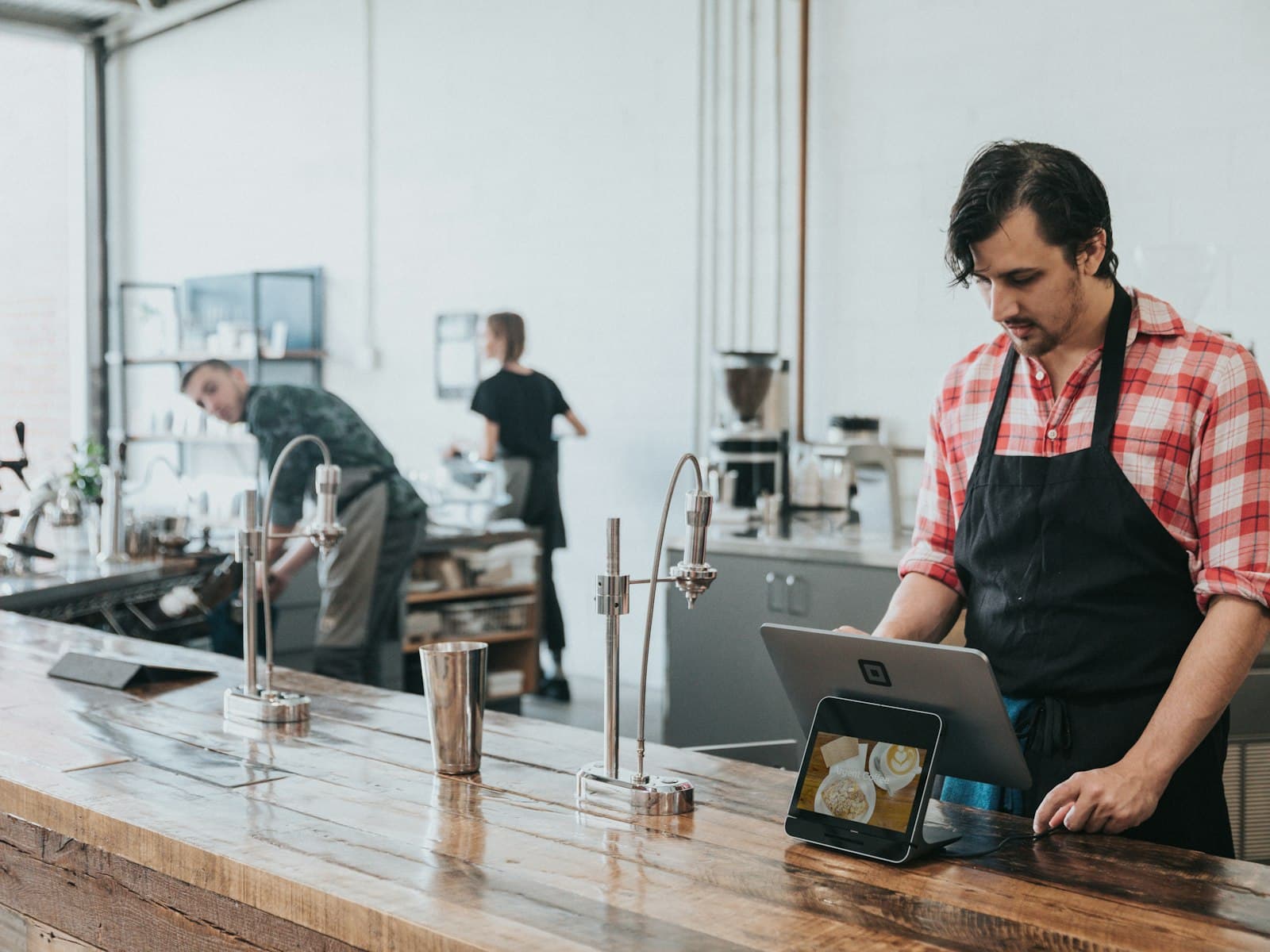Cafe owner managing orders on a tablet while running their coffee shop