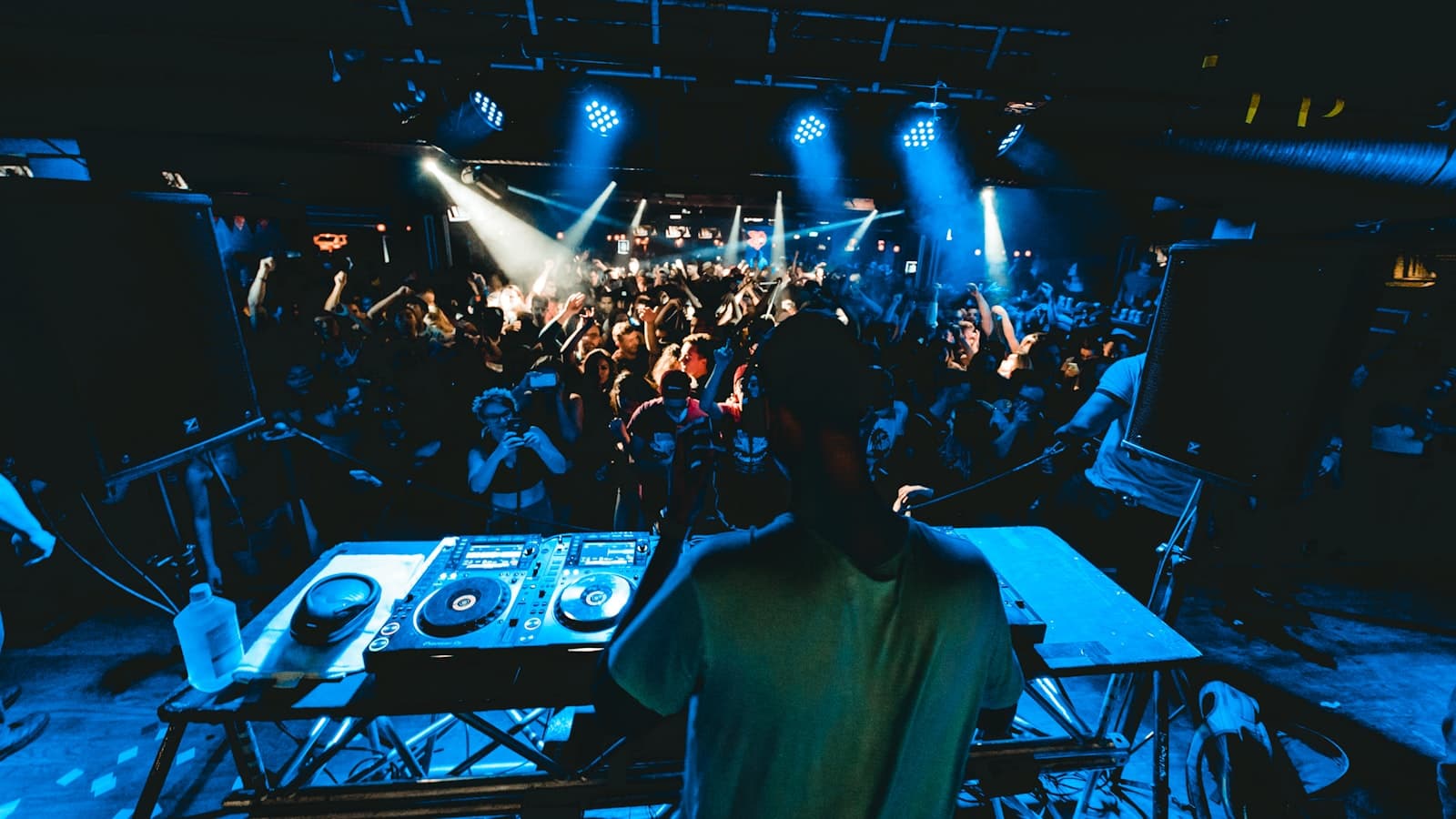 DJ performing to a packed crowd under dramatic stage lights